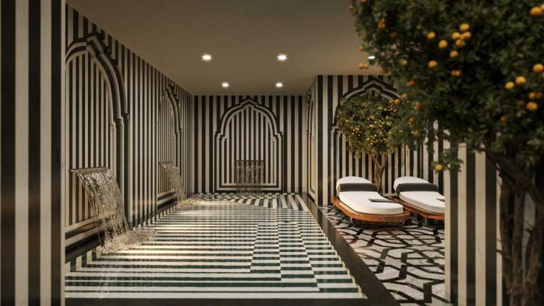 foto zona de aguas del spa del gran hotel Claridge granada. lleva un mosaico de marmol blanco y negro una piscina con dos cascadas de agua, dos tumbonas y un naranjo