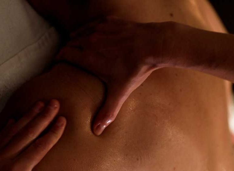 masje descontractuante de espalda en Wellness Boutique Granada. S eve la mano derecha apoyada en la zona alta del trapecio y la mano derecha en el deltoides